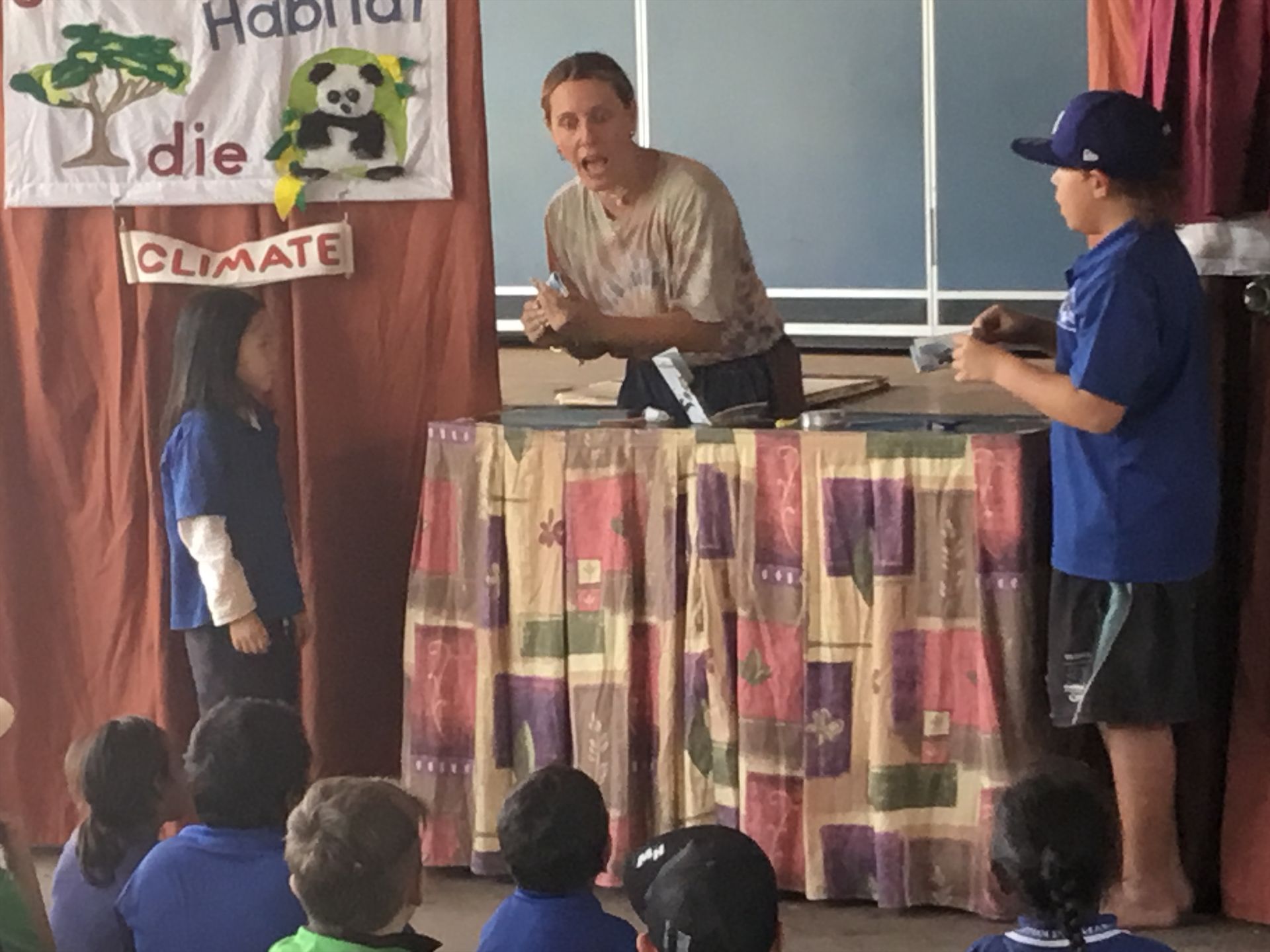 A group of children are sitting in front of a sign that says climate