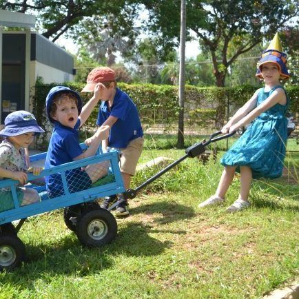 A group of children are pulling a blue wagon