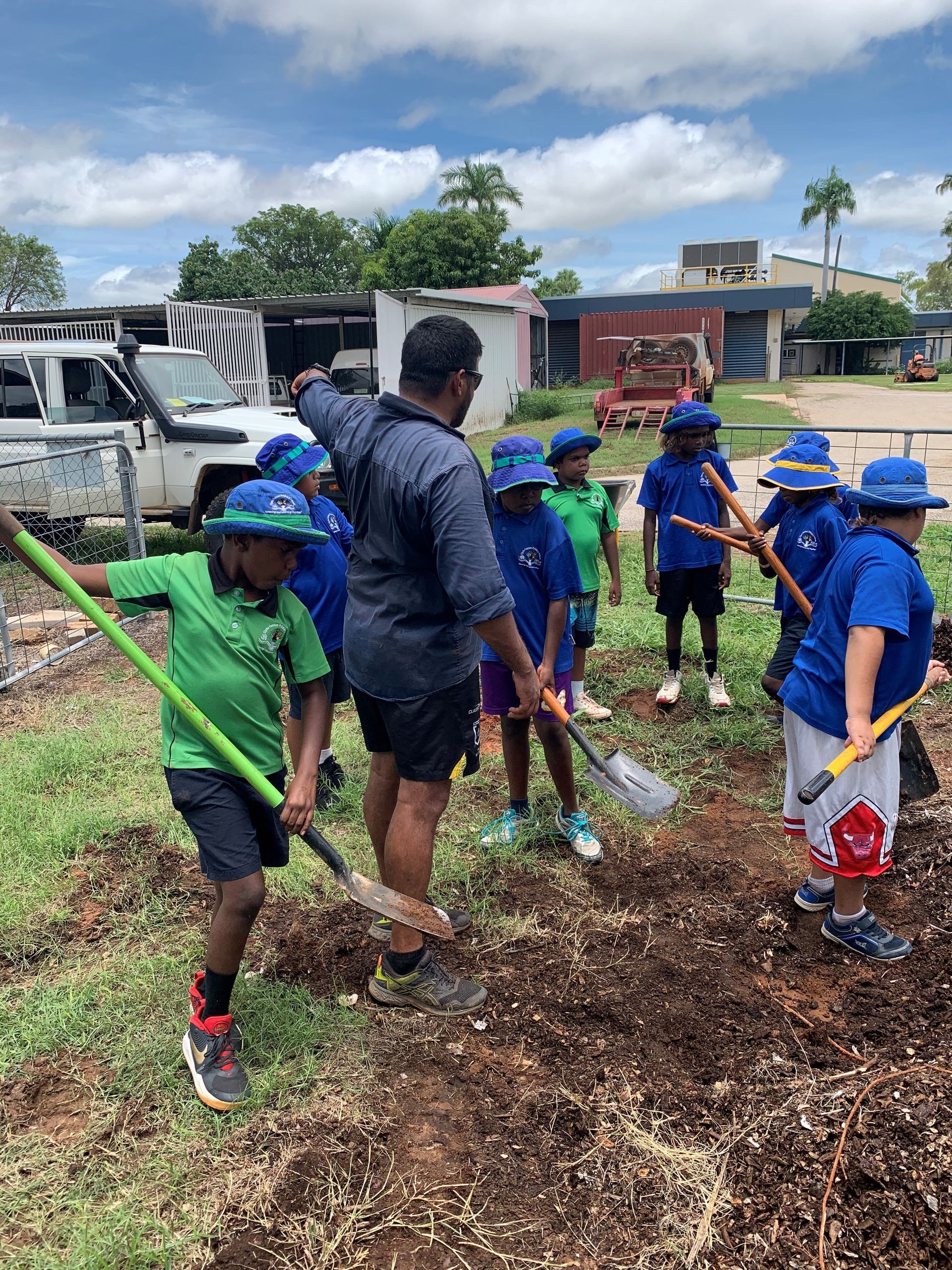 A group of children are digging in the dirt with shovels.