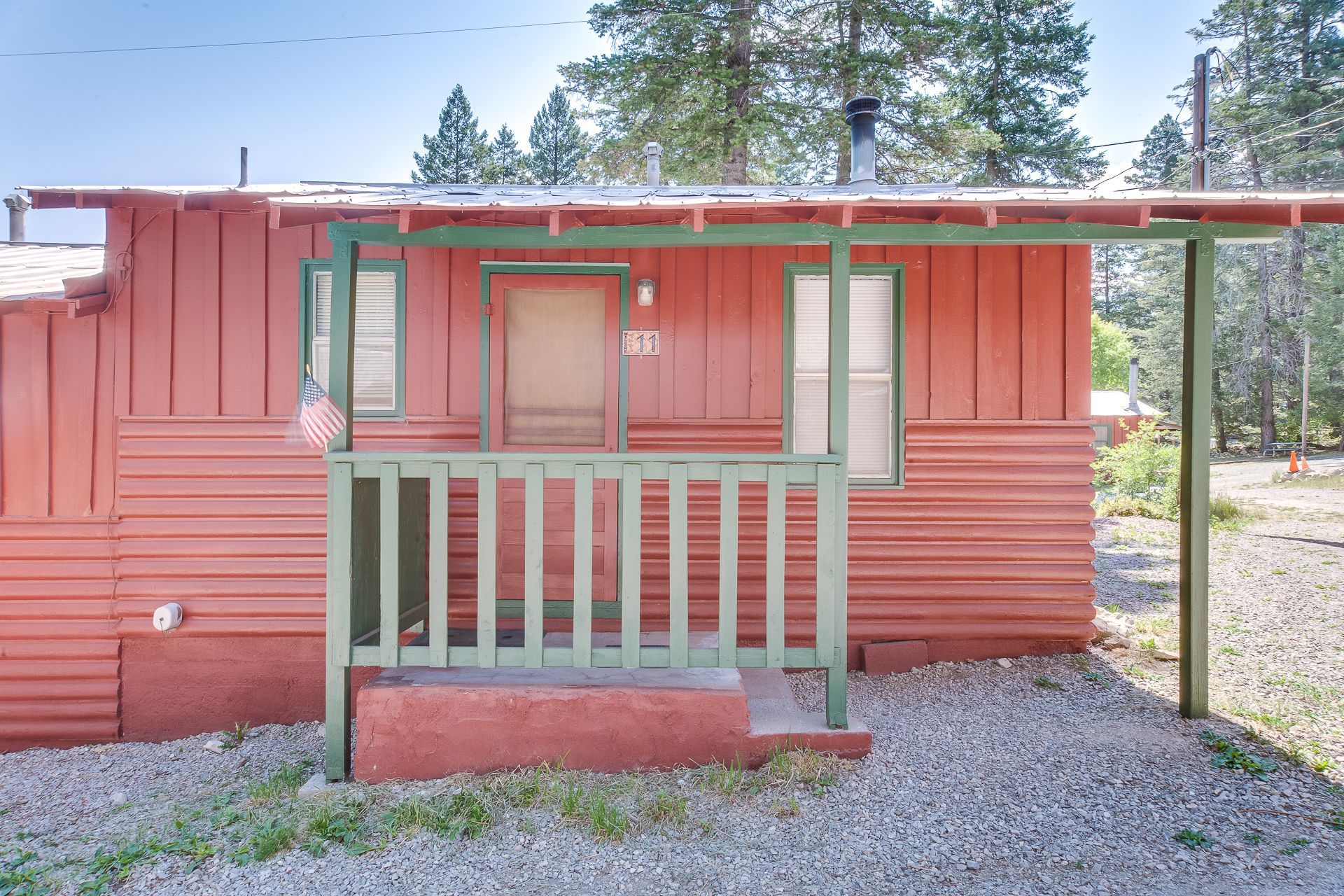 A small red house with a green porch and stairs.