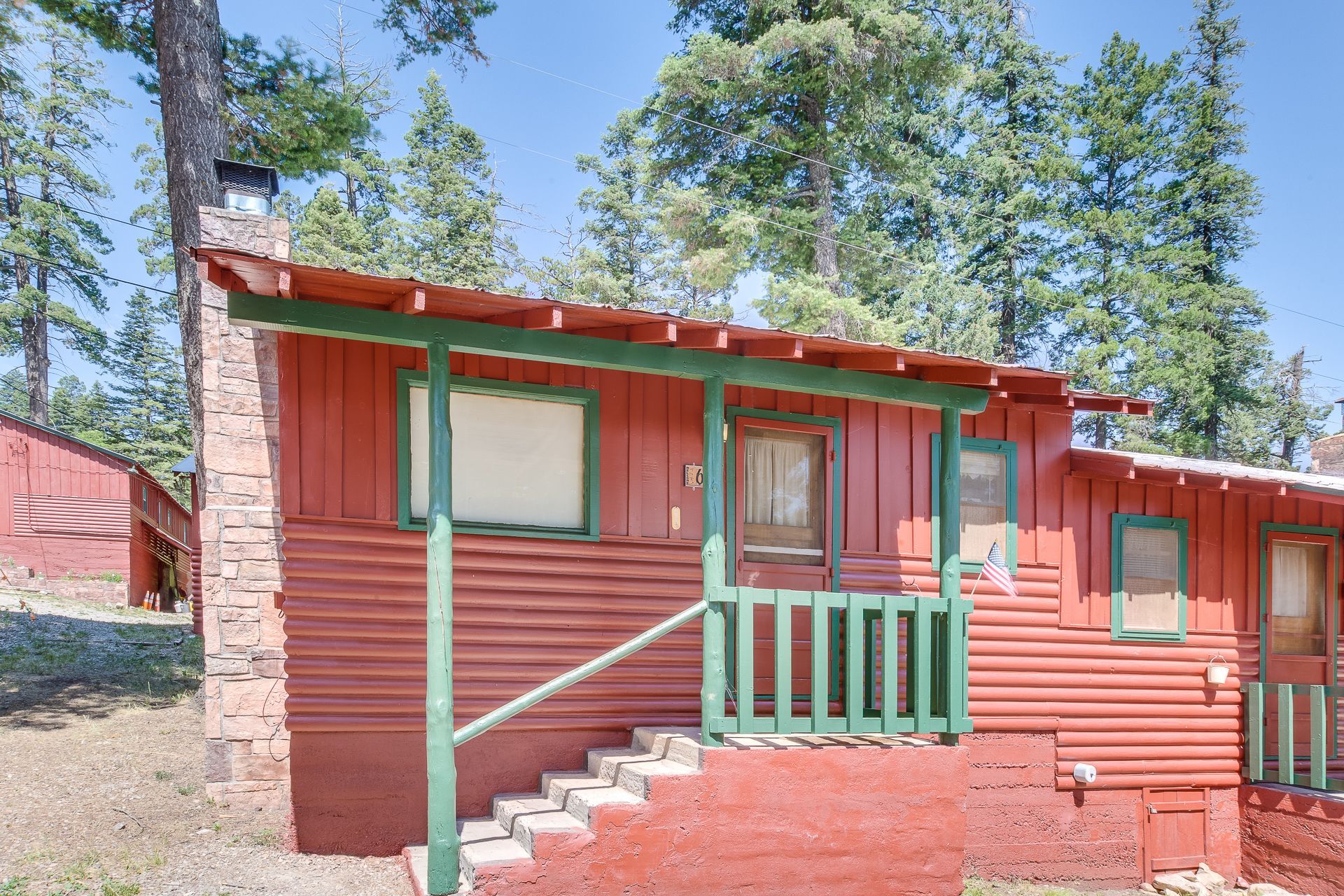 A small red house with a green porch and stairs.