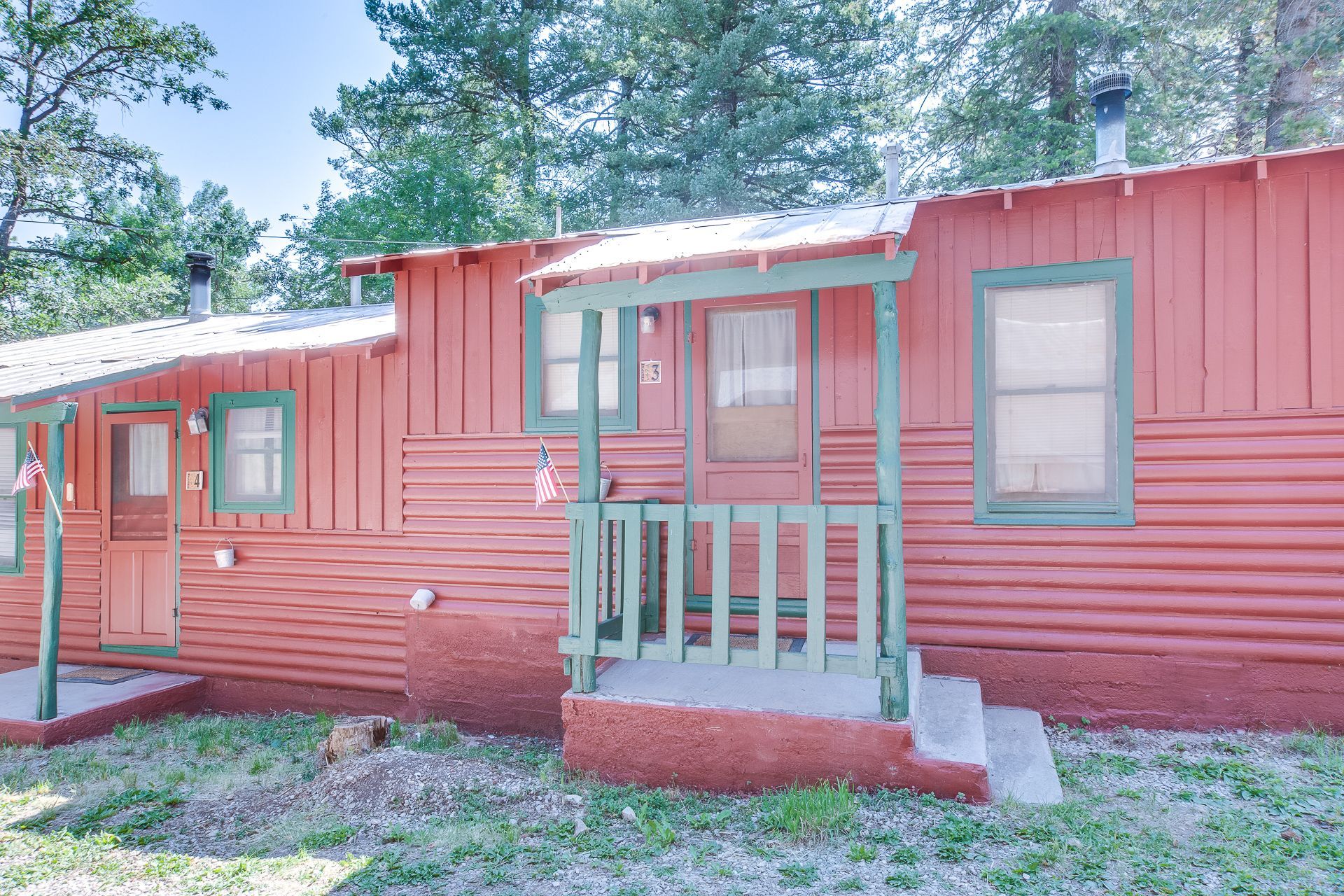 A red house with a green porch and windows