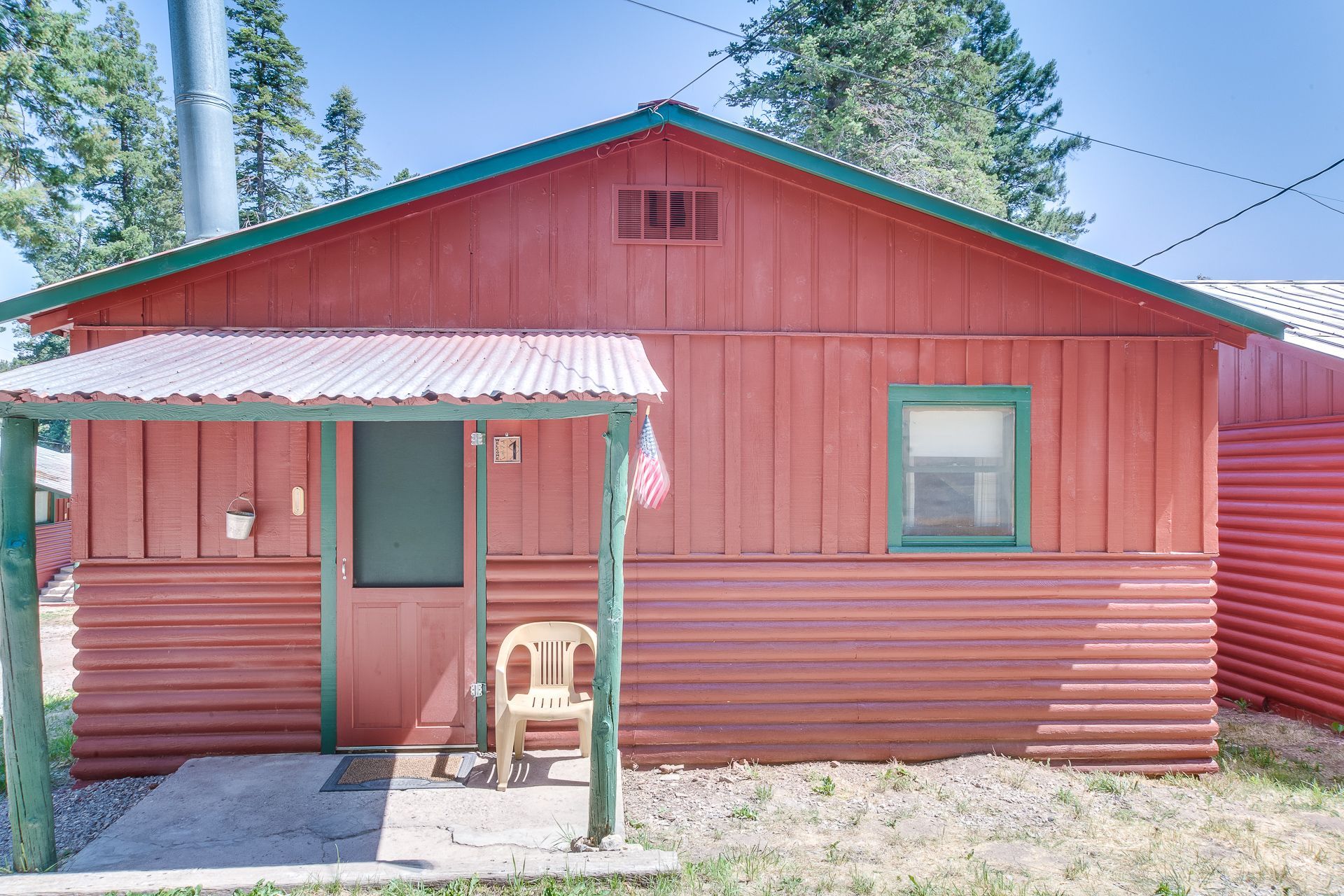 A red house with a green roof and a porch.