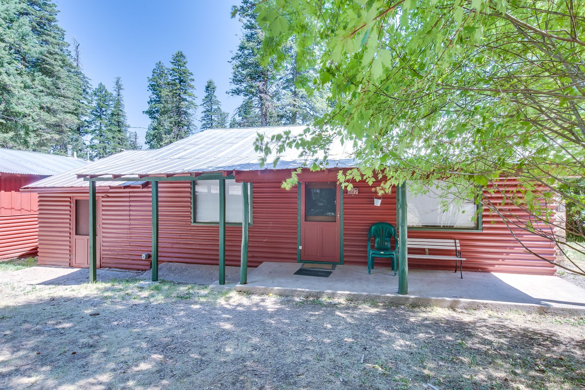 A red log cabin with a green chair on the porch.