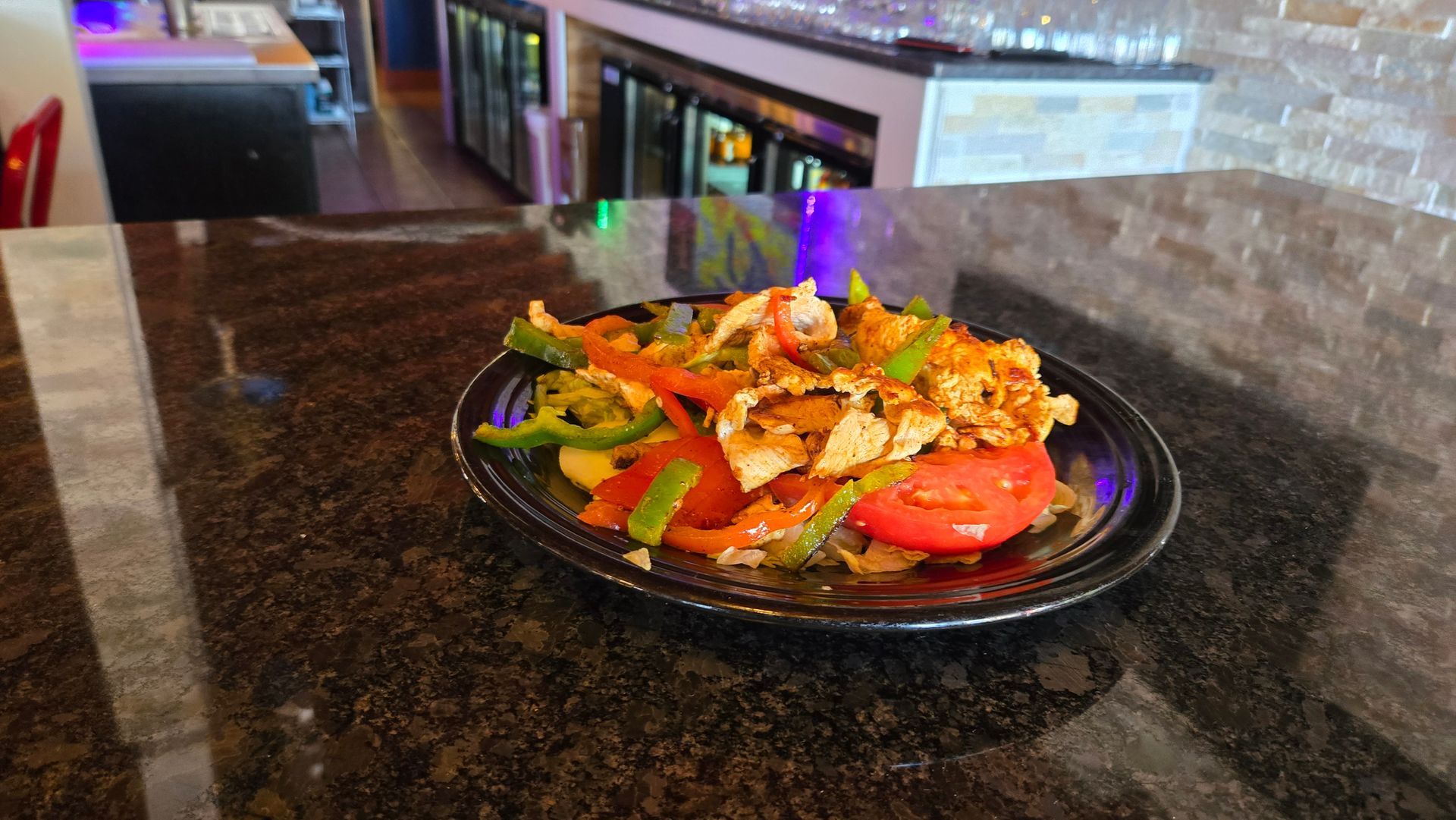 Nachos on a tray topped with cheese, olives, and meat, with salsa and guacamole.