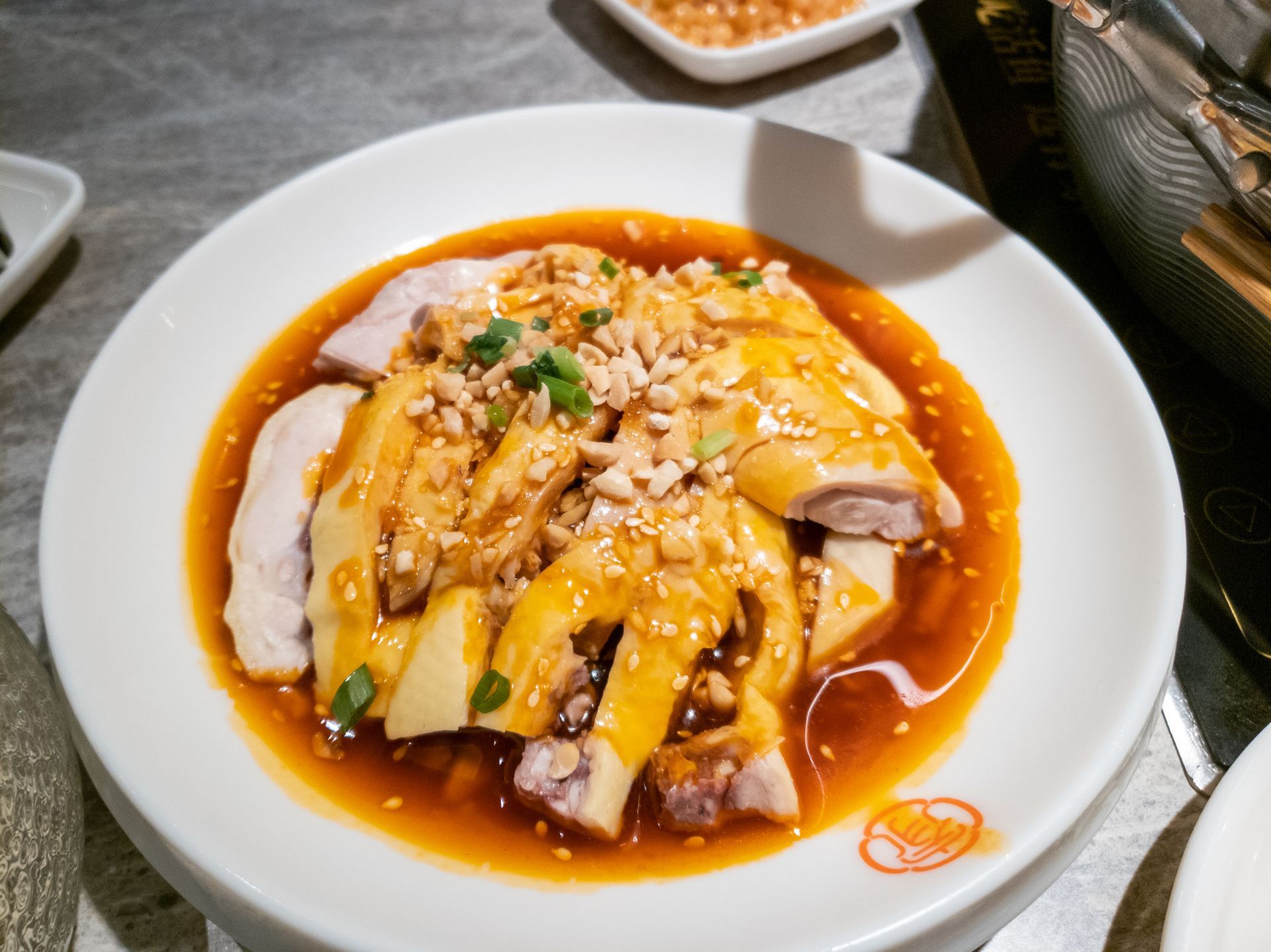 Plate of sliced chicken in sauce, topped with peanuts and green onions. Plate of sliced chicken in sauce, topped with peanuts and green onions.