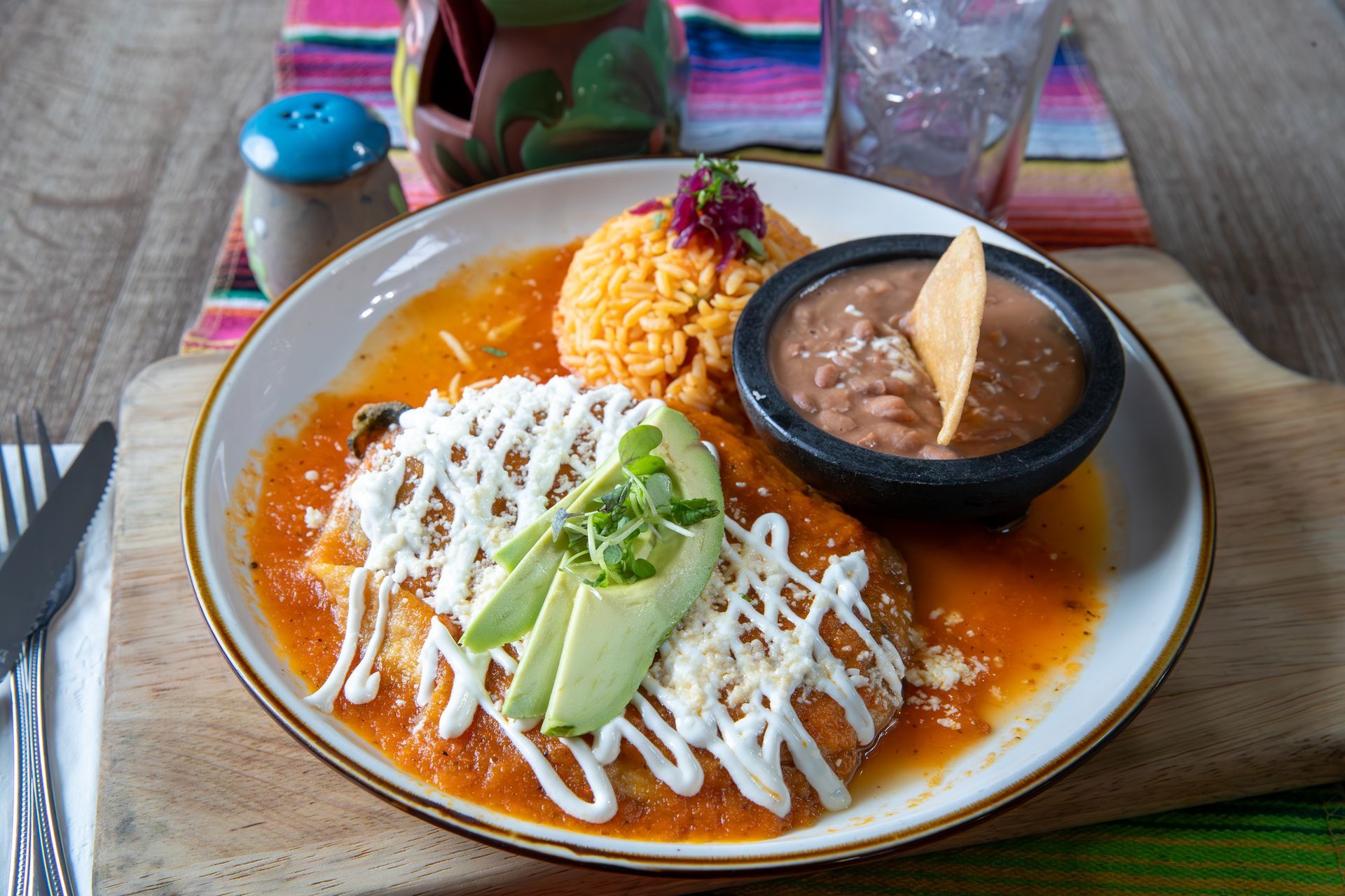 Enchiladas with rice, beans, and avocado on a plate. Enchiladas with rice, beans, and avocado on a plate.