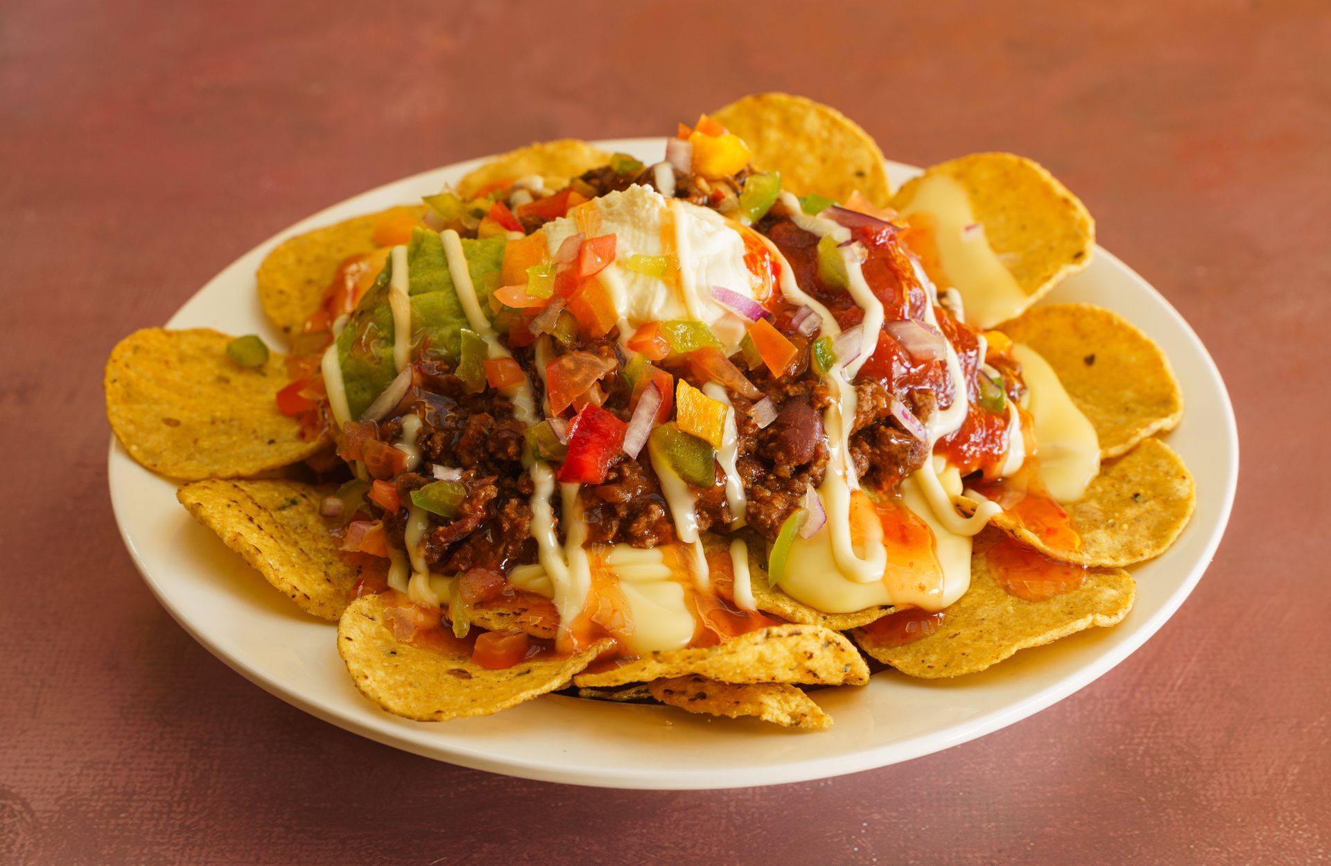Nachos with beef, cheese, avocado, and salsa on a white plate. Nachos with beef, cheese, avocado, and salsa on a white plate.