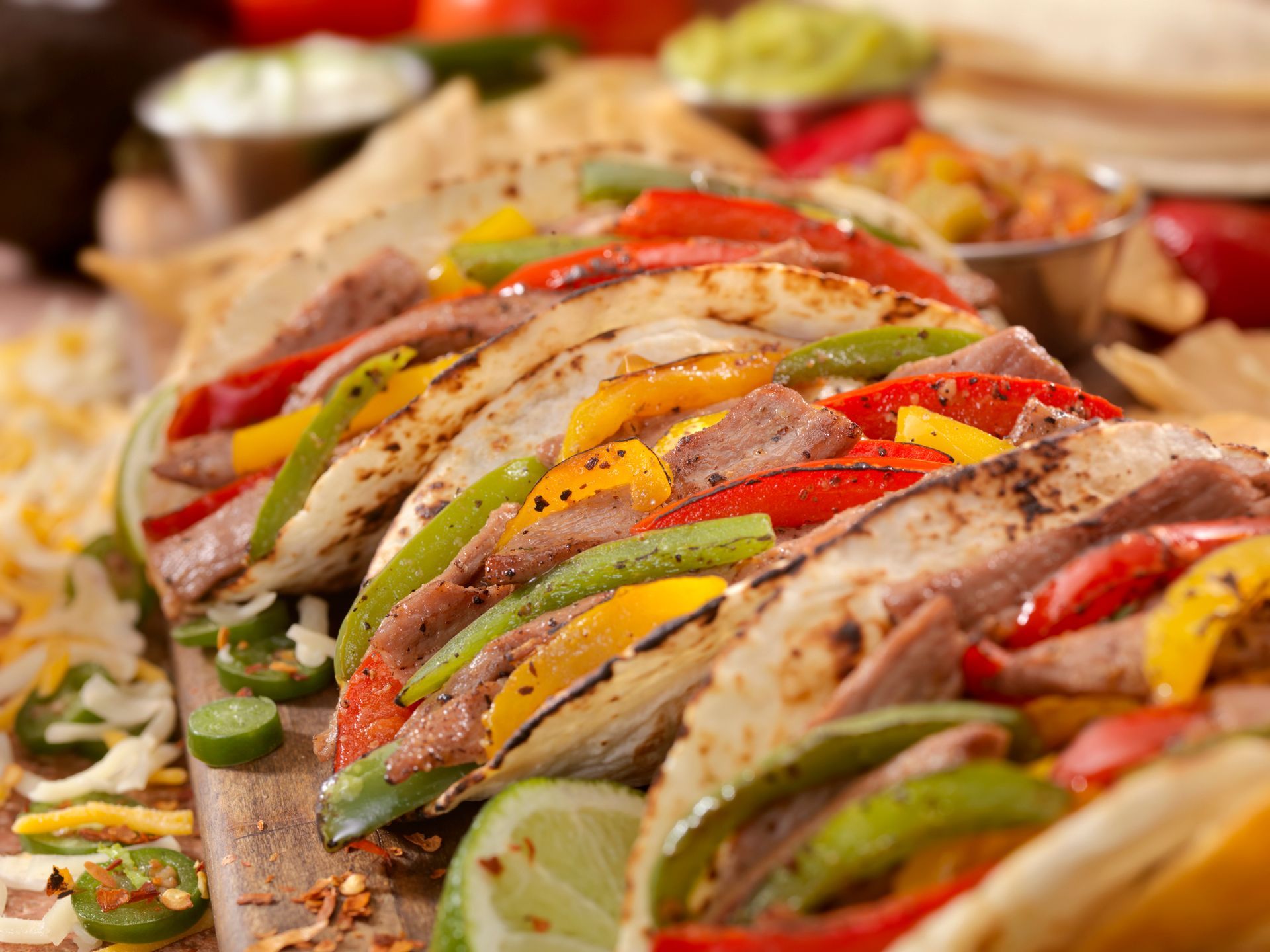 Grilled steak fajitas with colorful bell peppers, lime, and tortillas. Grilled steak fajitas with colorful bell peppers, lime, and tortillas.