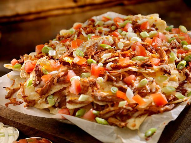 Nachos: Tortilla chips topped with shredded meat, cheese, tomatoes, and green onions.