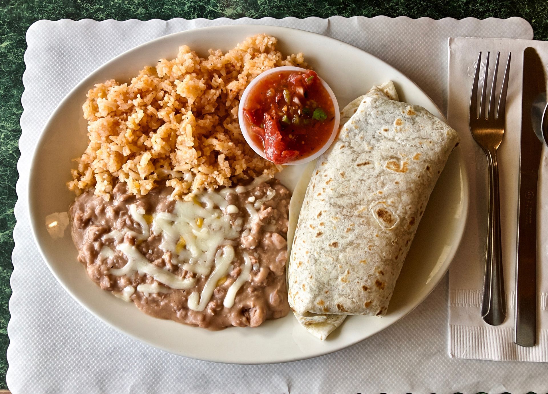 Plate with burrito, beans with cheese, rice, and salsa. Plate with burrito, beans with cheese, rice, and salsa.