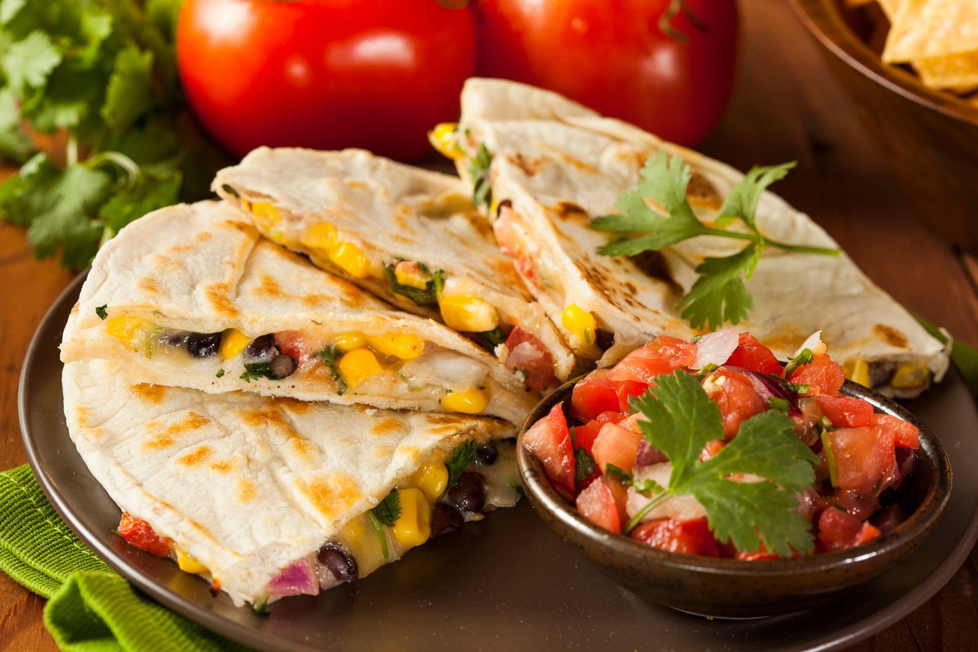 Quesadillas with salsa, tomatoes, corn, black beans, and cilantro on a plate.