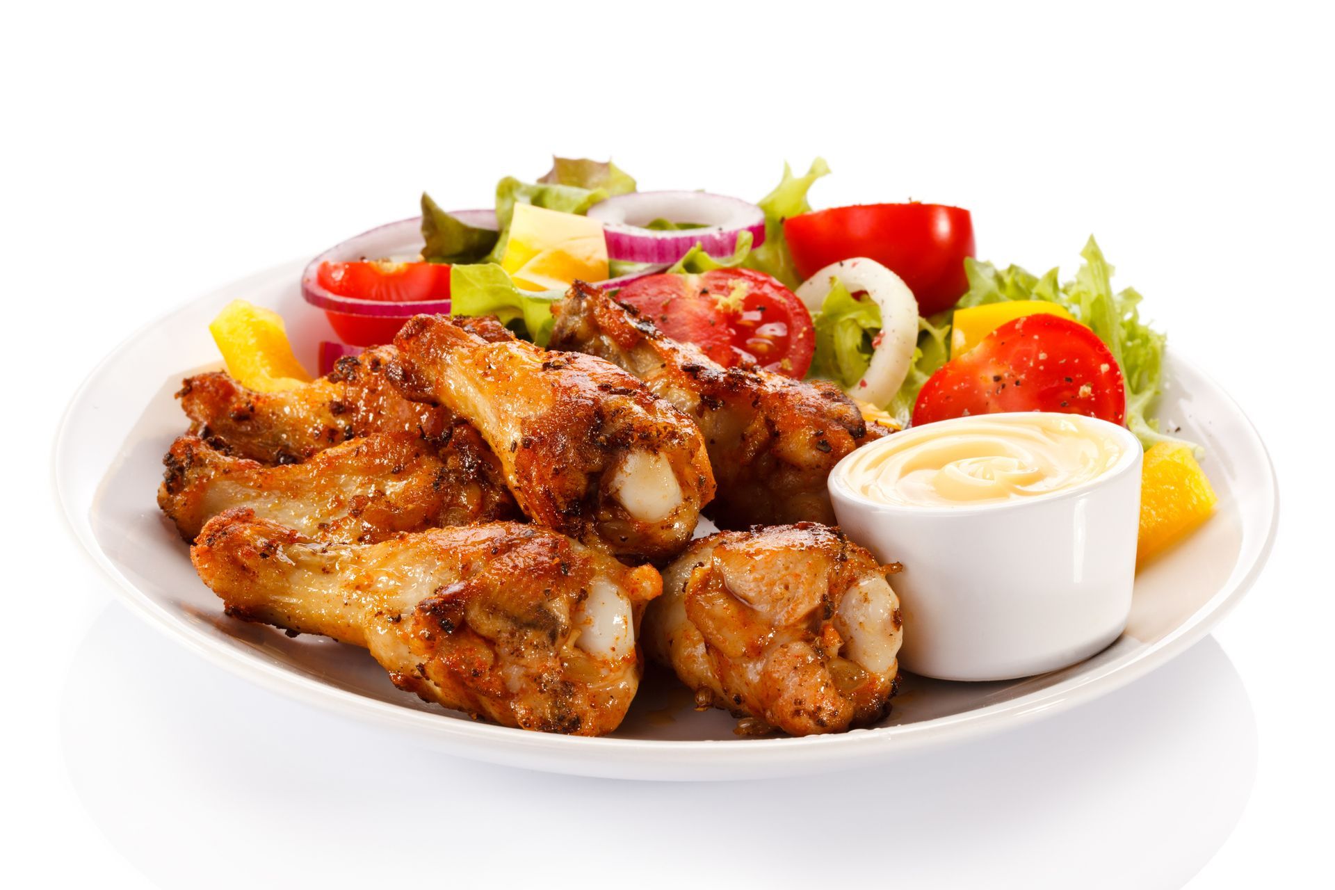 Chicken wings with salad and dipping sauce on a white plate.