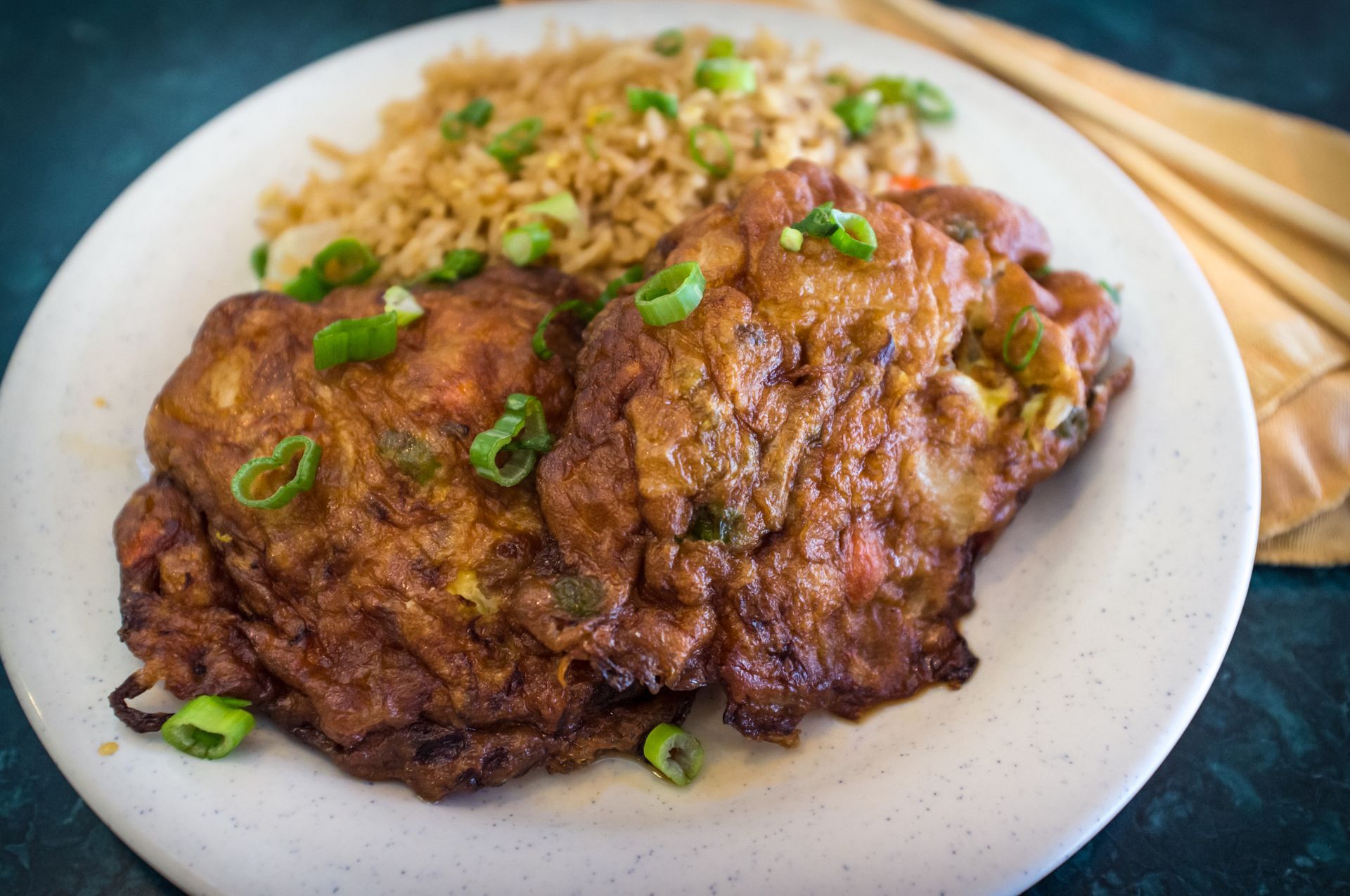Egg foo young with fried rice, garnished with green onions on a white plate.