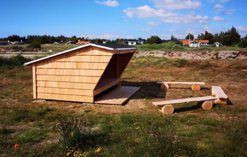 Et shelter i træ med et picnicbord foran