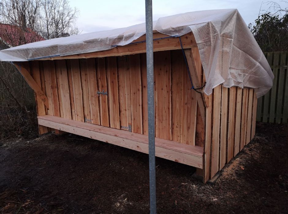 Et træskur med en presenning ovenpå