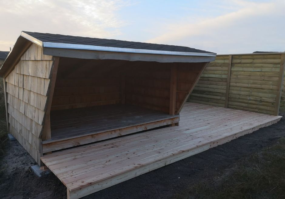 Et træskur med tag og træterrasse