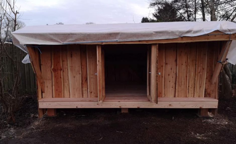 Et træskur med en presenning ovenpå.