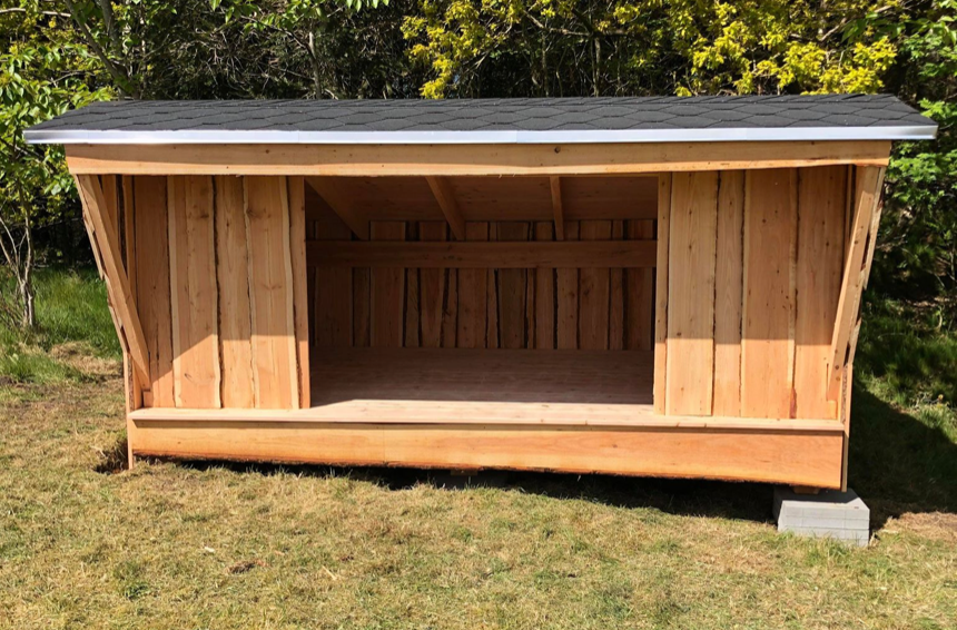 Et træskur står midt på en græsmark.