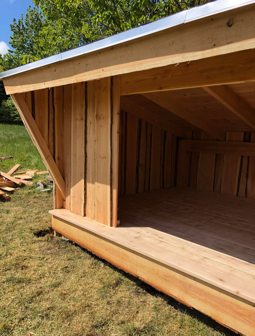 Et træskur står midt på en græsmark.