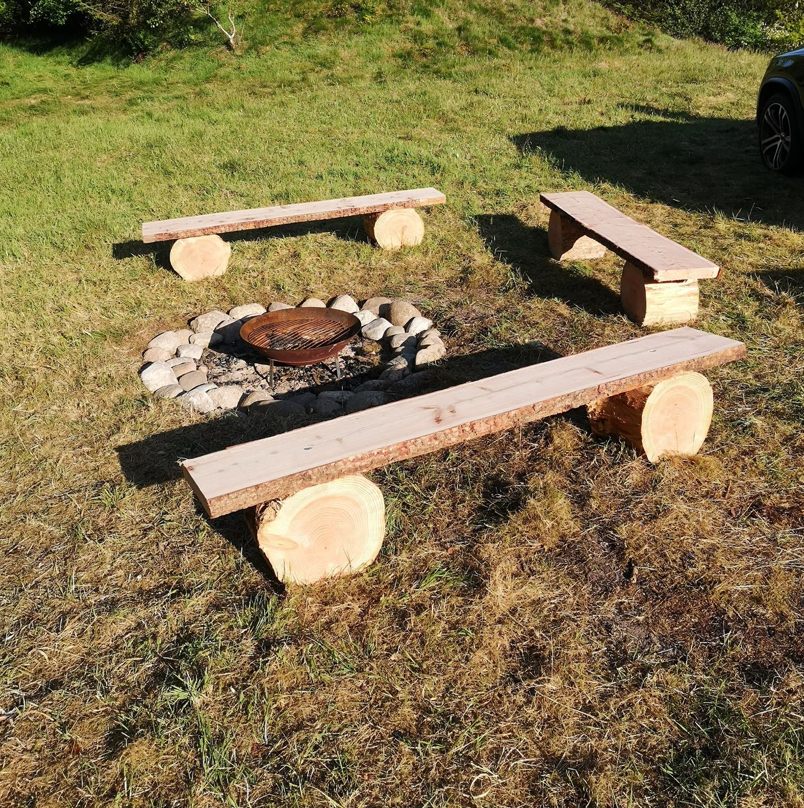 En gruppe træbænke omkring en bålplads