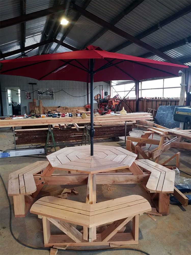 Et picnicbord i træ med bænke og en paraply i et lager.