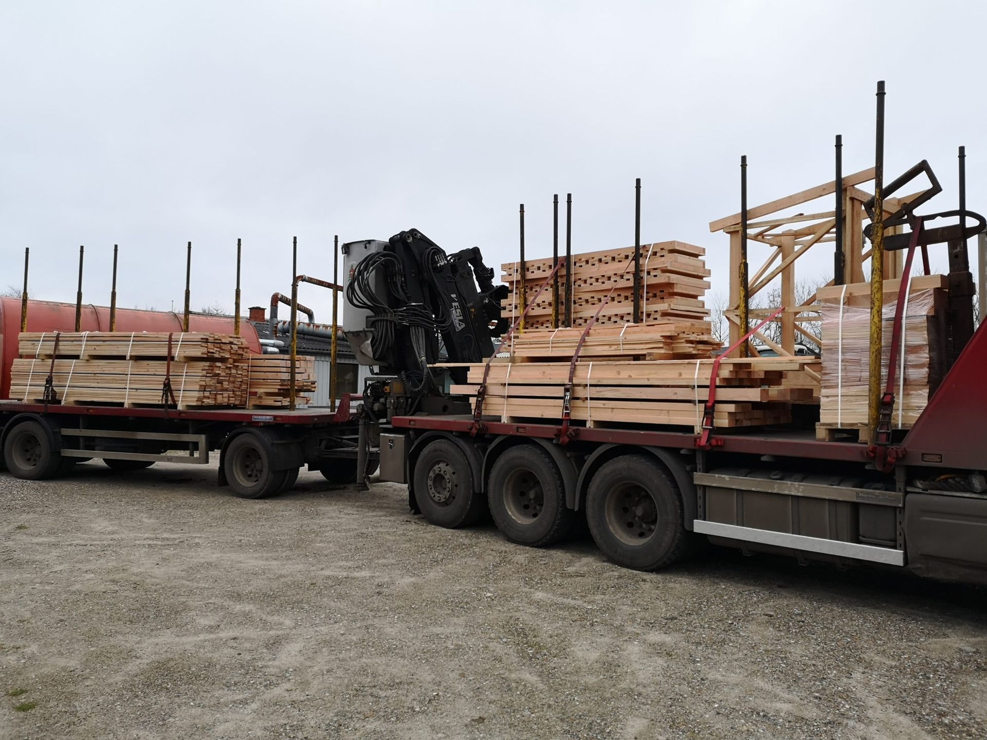En lastbil er læsset med træpaller og en kran.