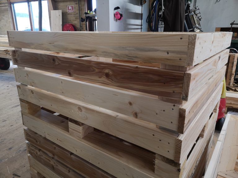 En stak træpaller er stablet oven på hinanden i et rum.