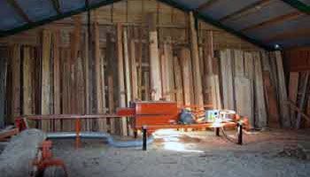 Et lager fyldt med masser af træbrædder og en bænk.