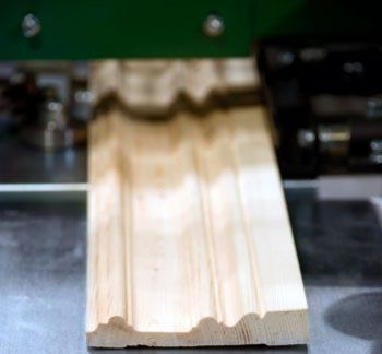 Et stykke træ bliver skåret af en maskine.