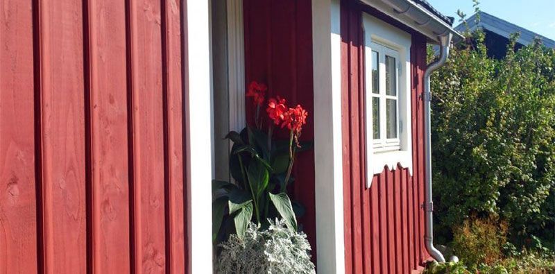 Et rødt hus med et vindue og blomster foran