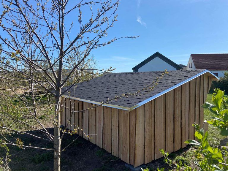 Et træskur med tag og et træ foran