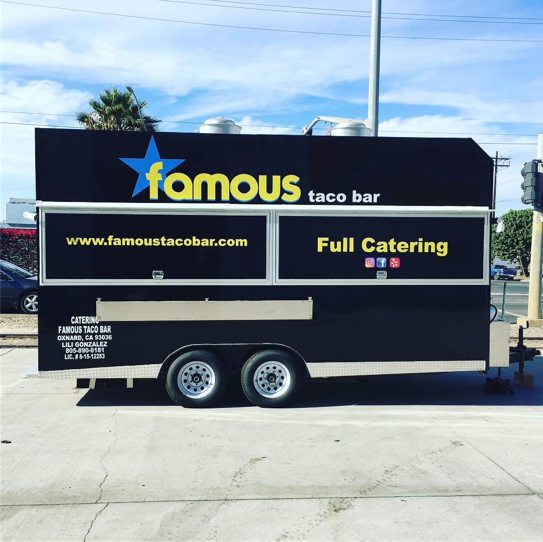 A famous taco bar trailer is parked on the side of the road