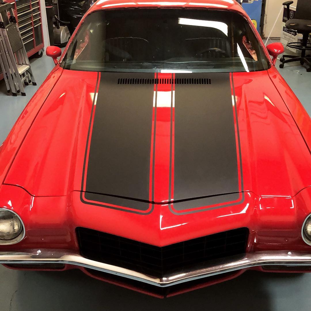 A red car with black stripes on the hood