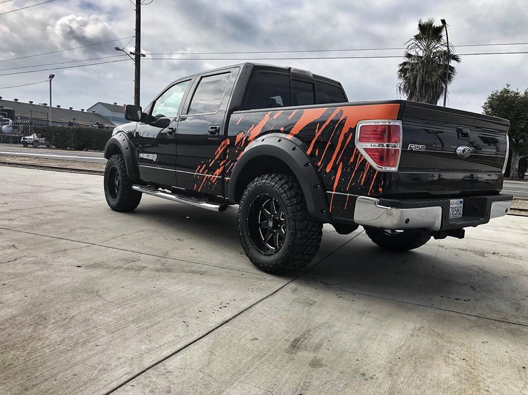 A black and orange truck is parked in a parking lot.