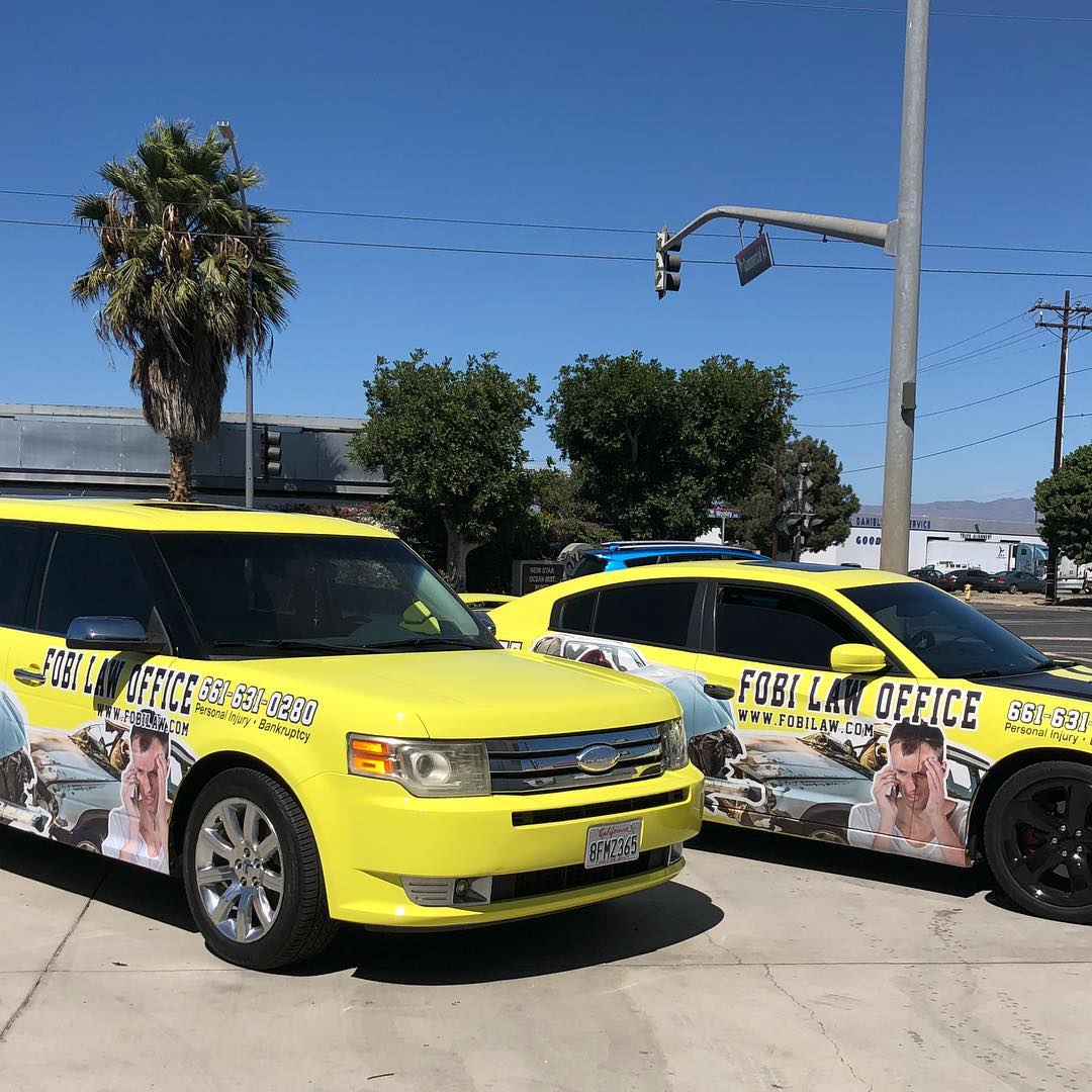 Two yellow cars are parked next to each other on the side of the road.