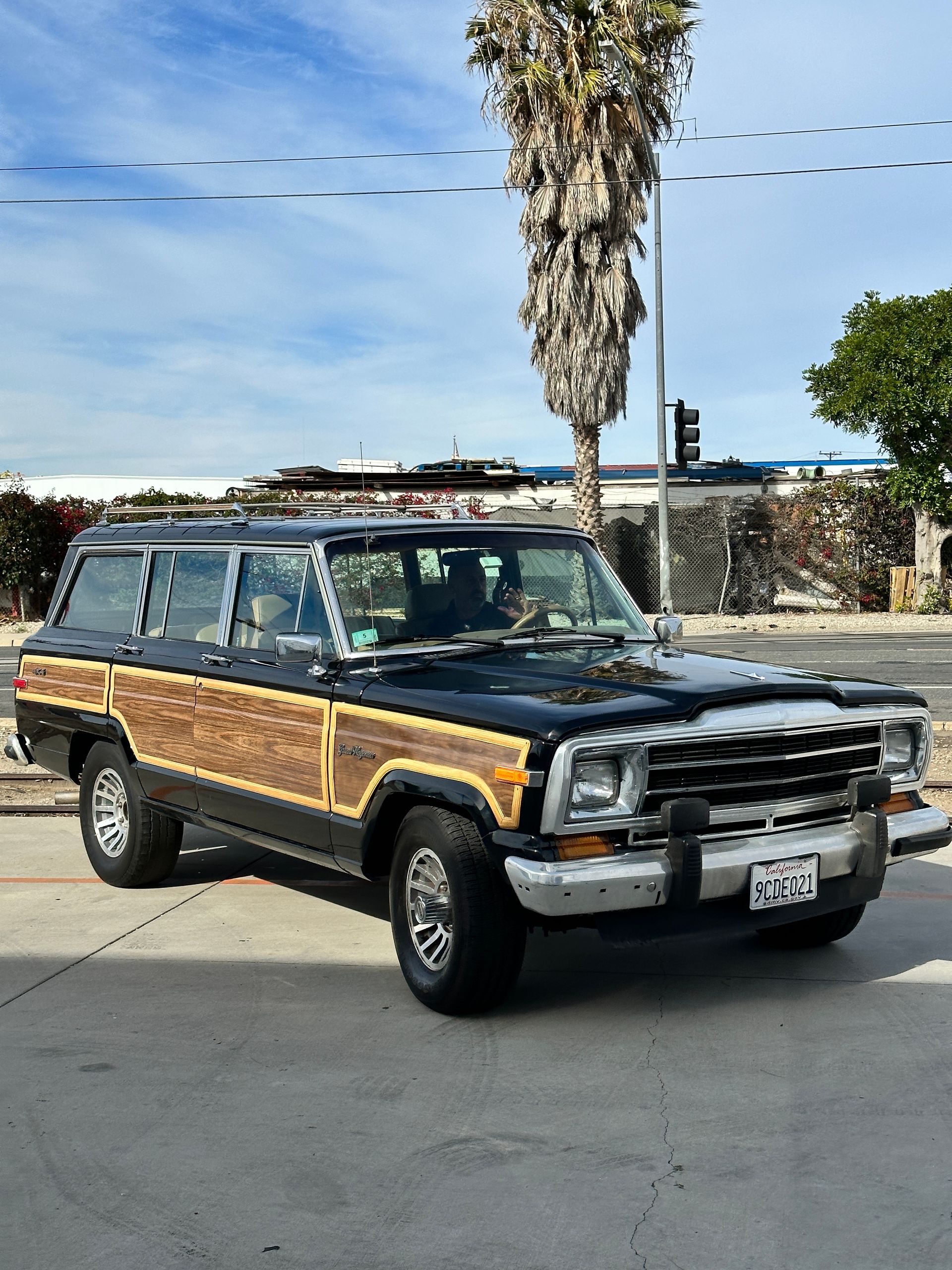 A black and wooden jeep is parked on the side of the road