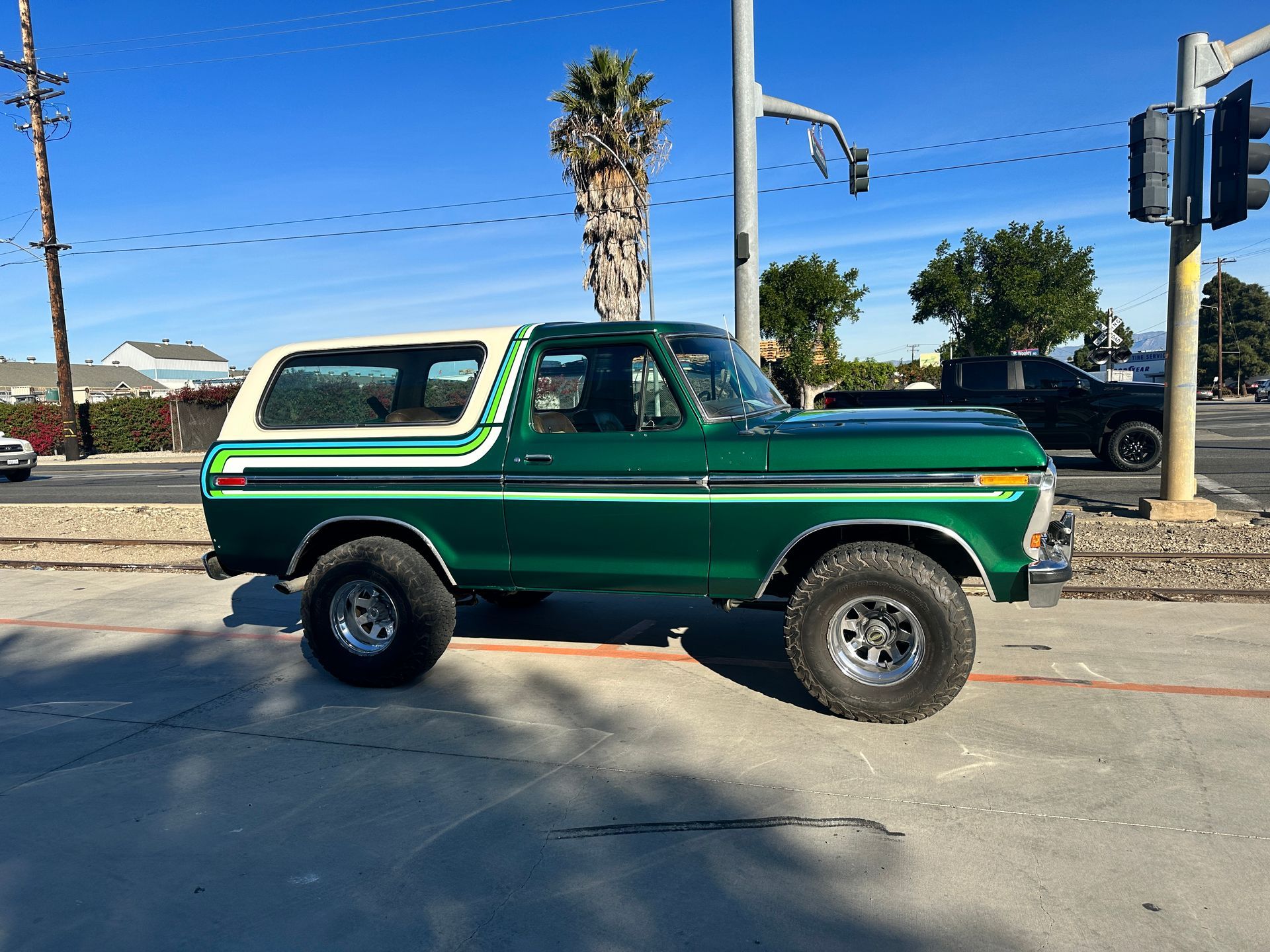 A green ford bronco is parked on the side of the road