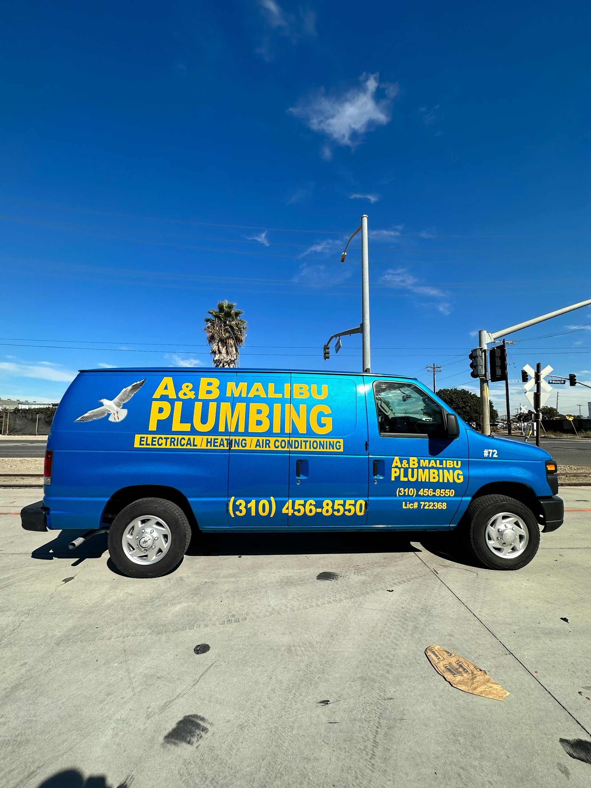 A blue plumbing van is parked on the side of the road