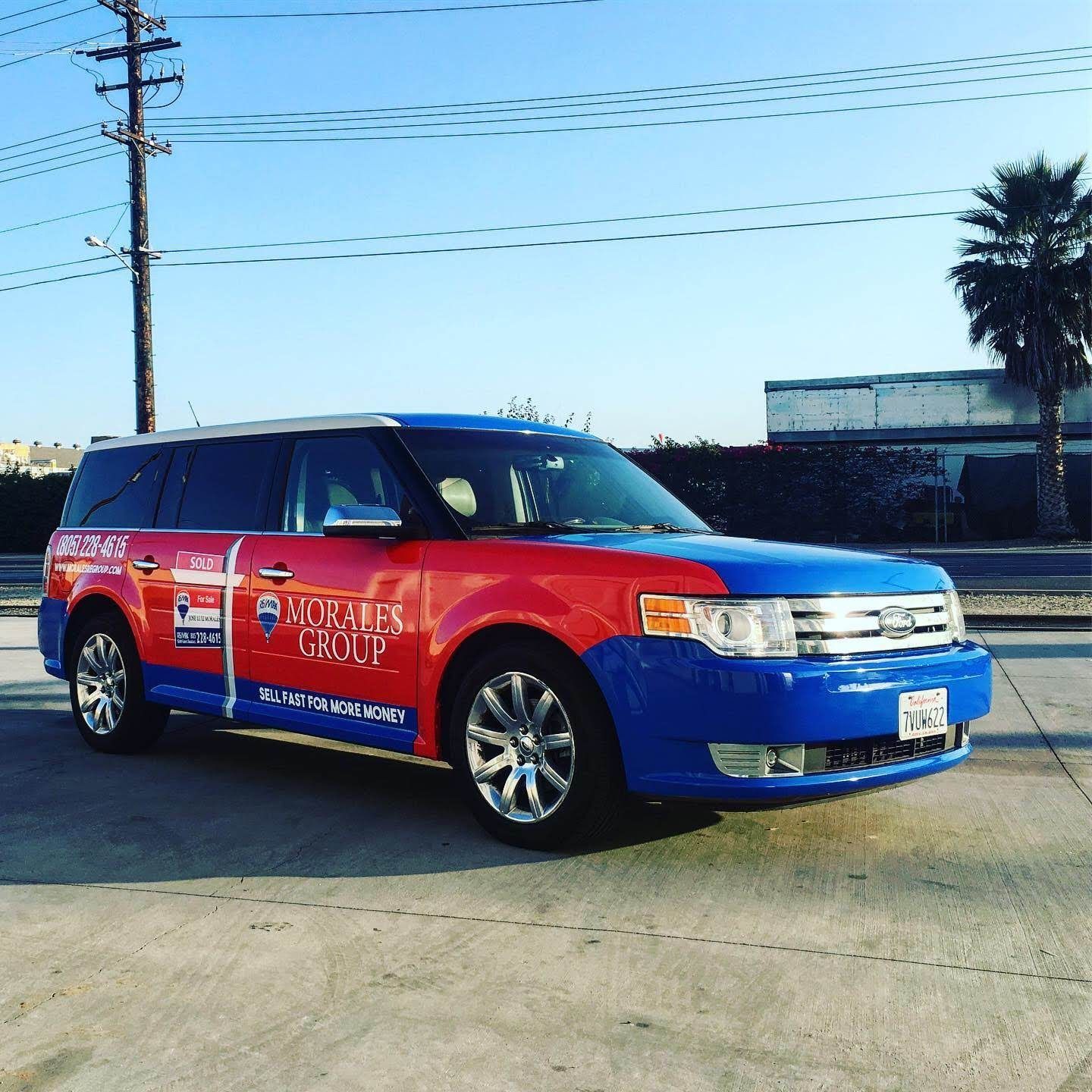 A red and blue ford flex is parked on the side of the road