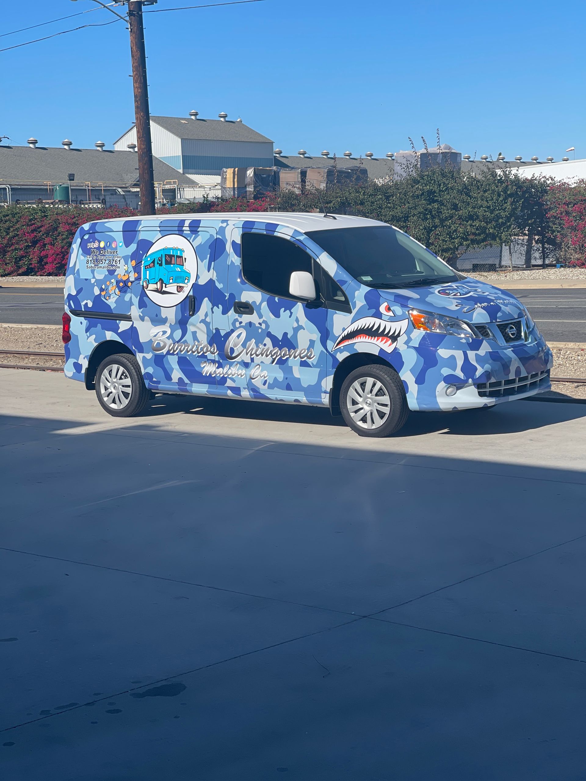 A blue camouflage van is parked on the side of the road.