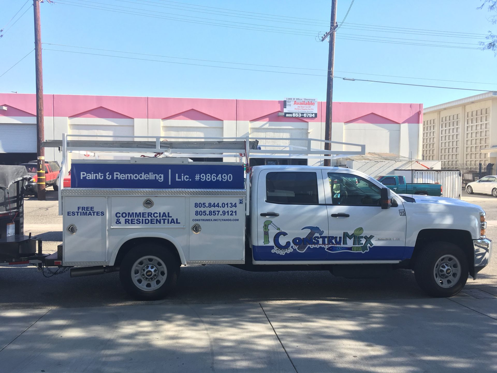 A white and blue utility truck is parked in front of a building.