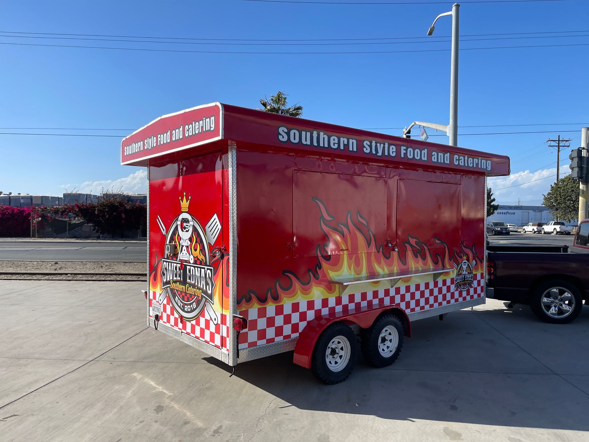 A red trailer with flames on it is parked next to a truck.