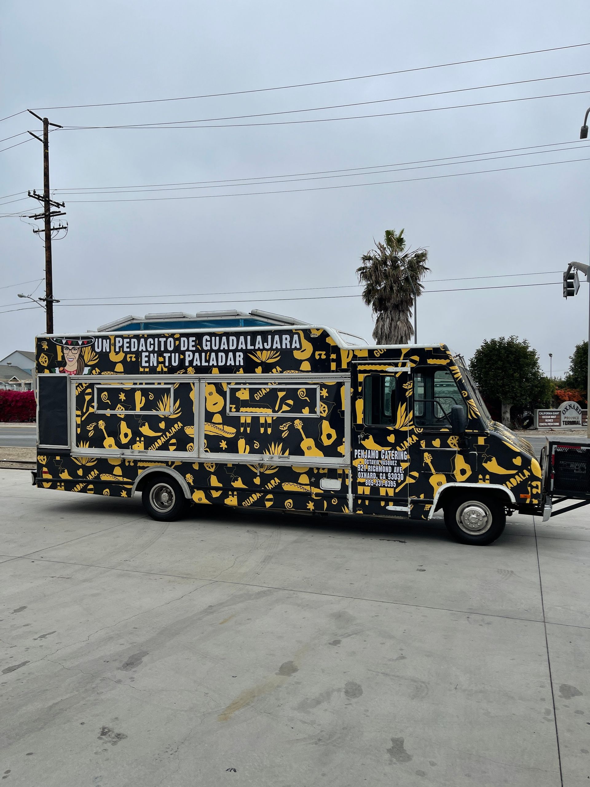 A black and yellow food truck is parked in a parking lot