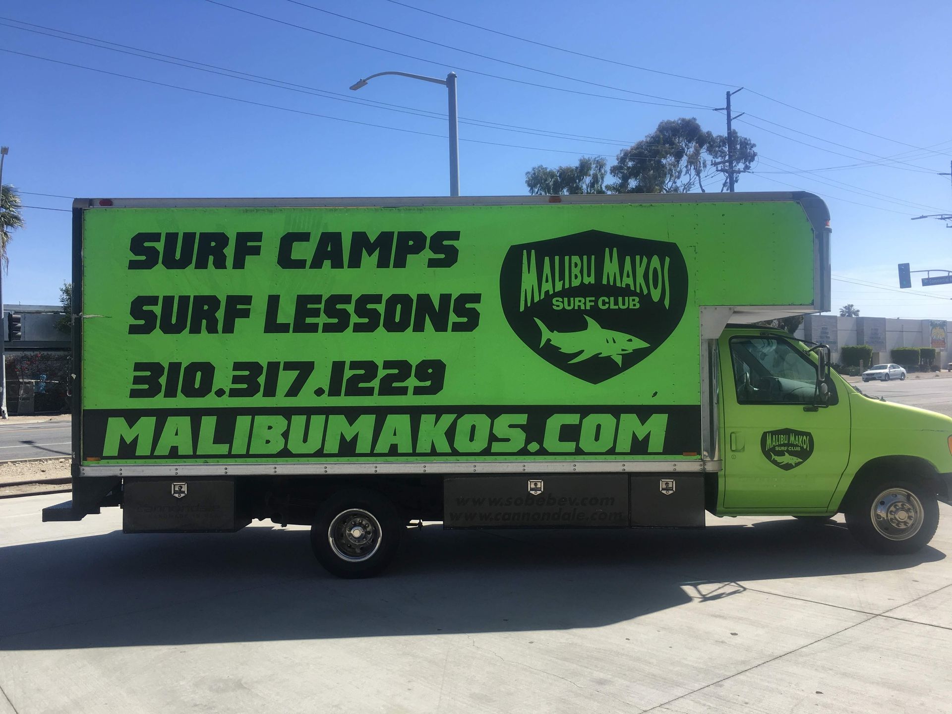 A green truck that says surf camps surf lessons on it