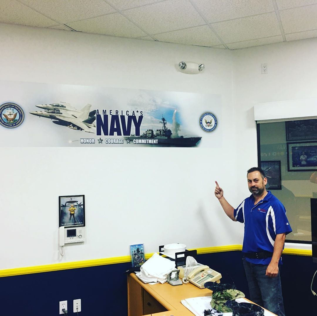 A man standing in front of a navy sign