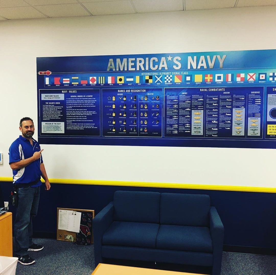 A man stands in front of a wall that says america 's navy