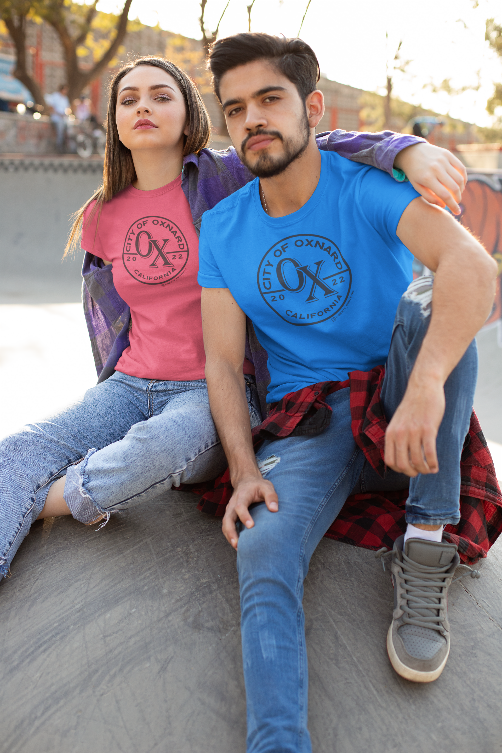 A man and a woman are sitting next to each other on a sidewalk.
