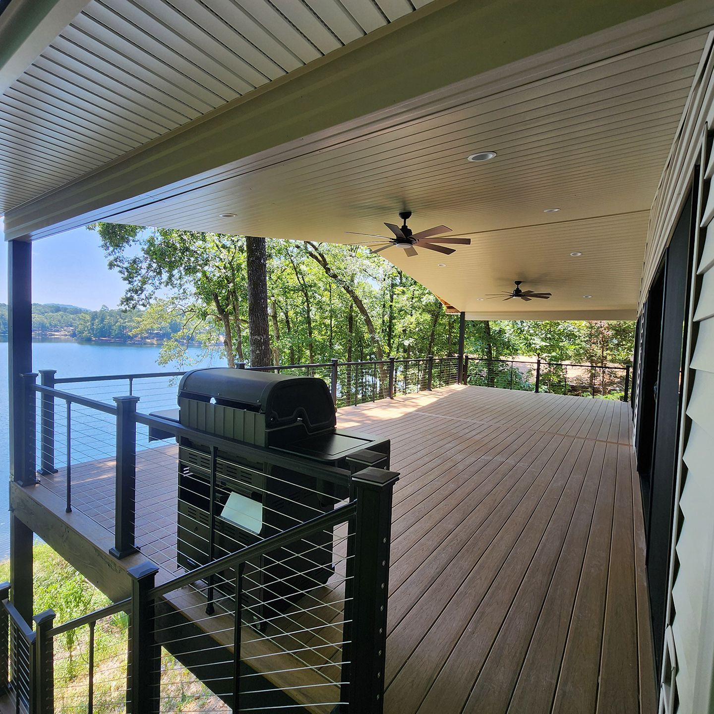 A large deck with a ceiling fan overlooking a lake