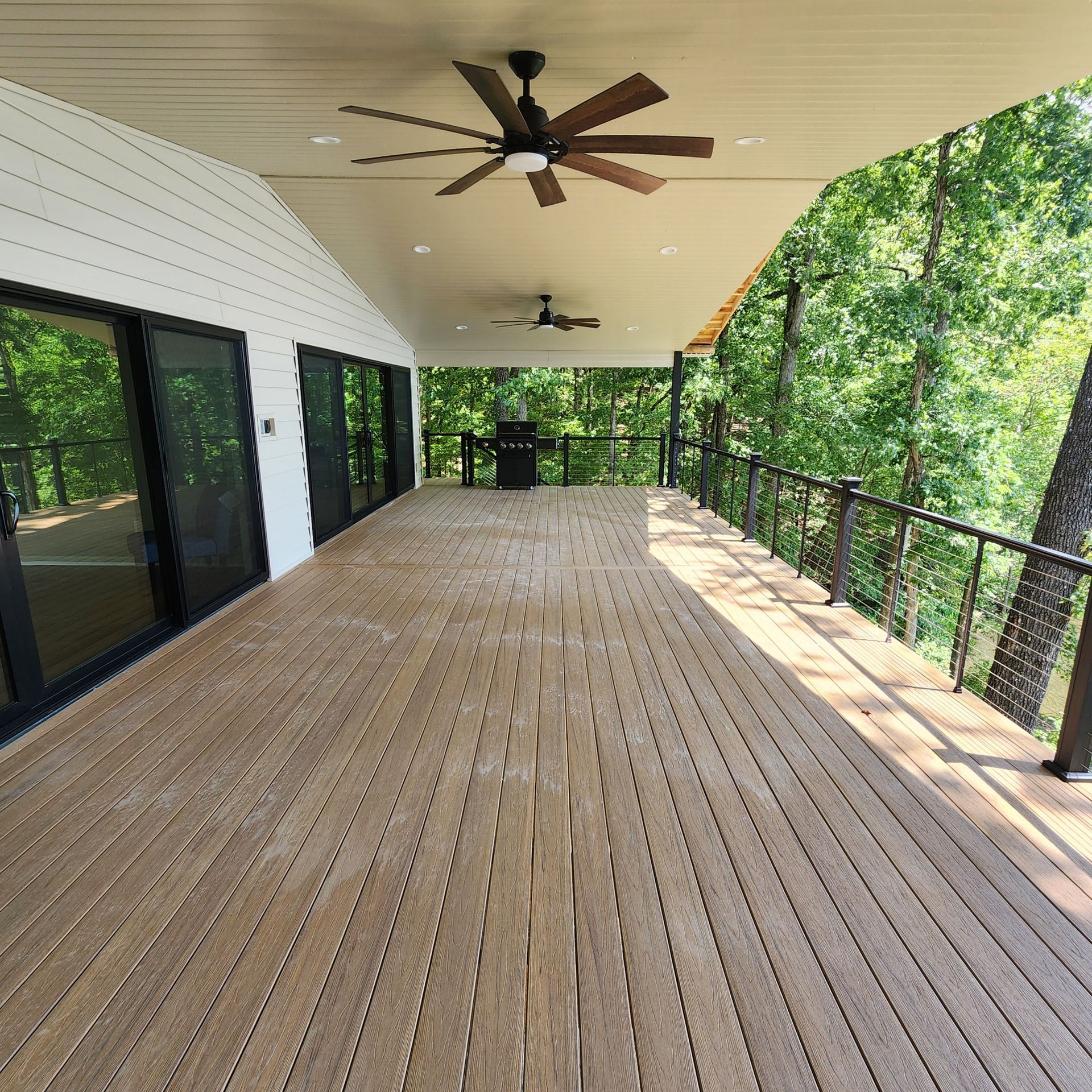 A large wooden deck with a ceiling fan